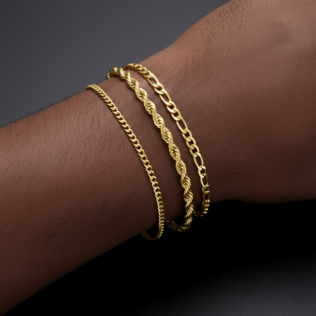 Gold chain bracelets on a wrist against a dark background