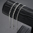 3 silver chains bracelet  on a black leather surface with a gray background