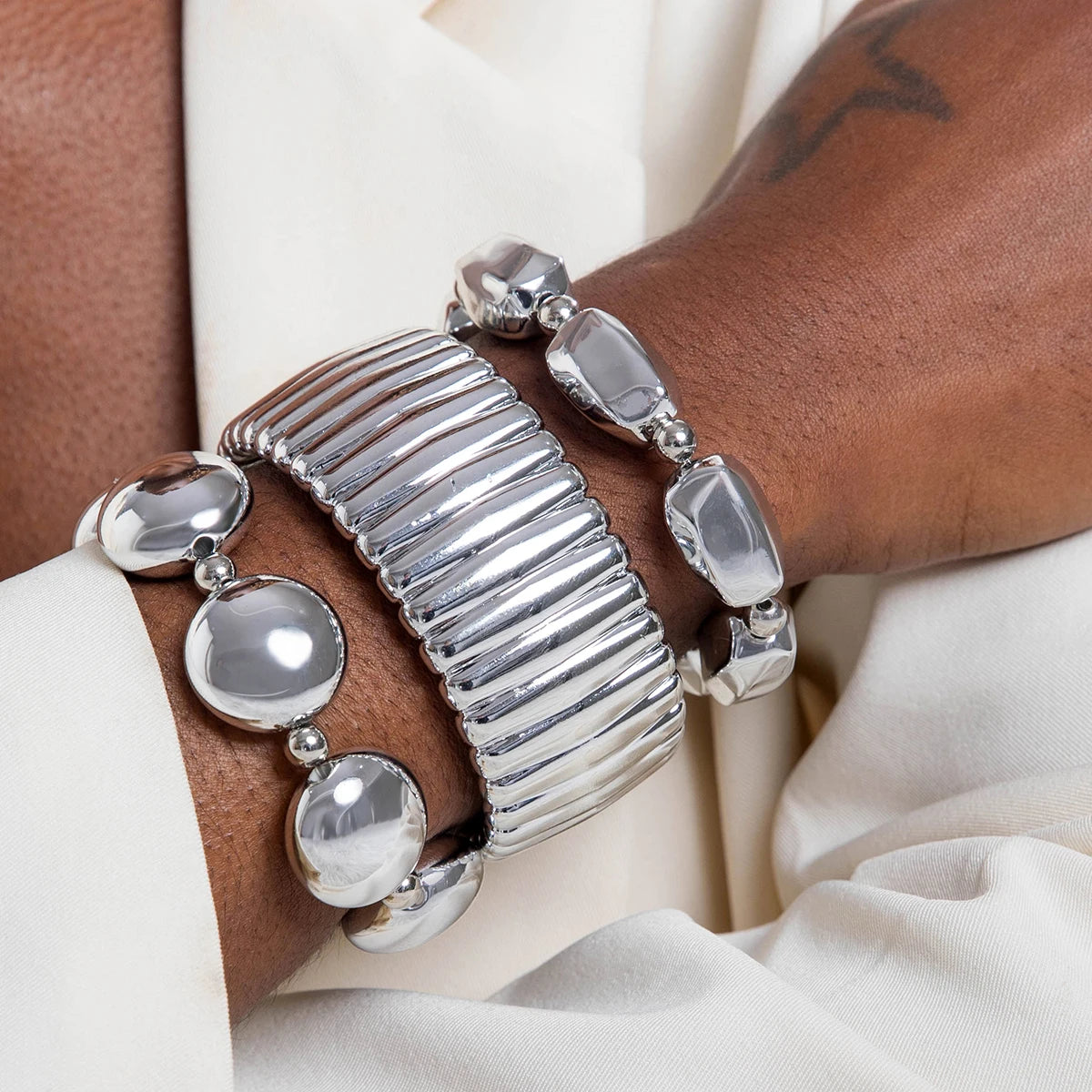 Silver bangle on a wrist with a neutral background
