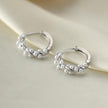 Silver hoop earrings with pearl-like beads on a beige fabric background