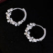 Silver hoop earrings with pearl-like beads on a dark surface