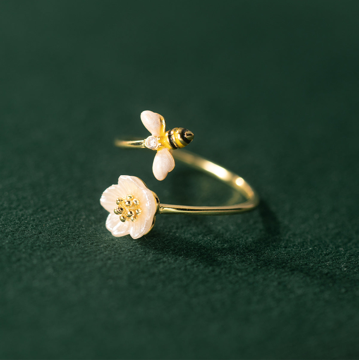 Gold rings with floral designs on a dark green background
