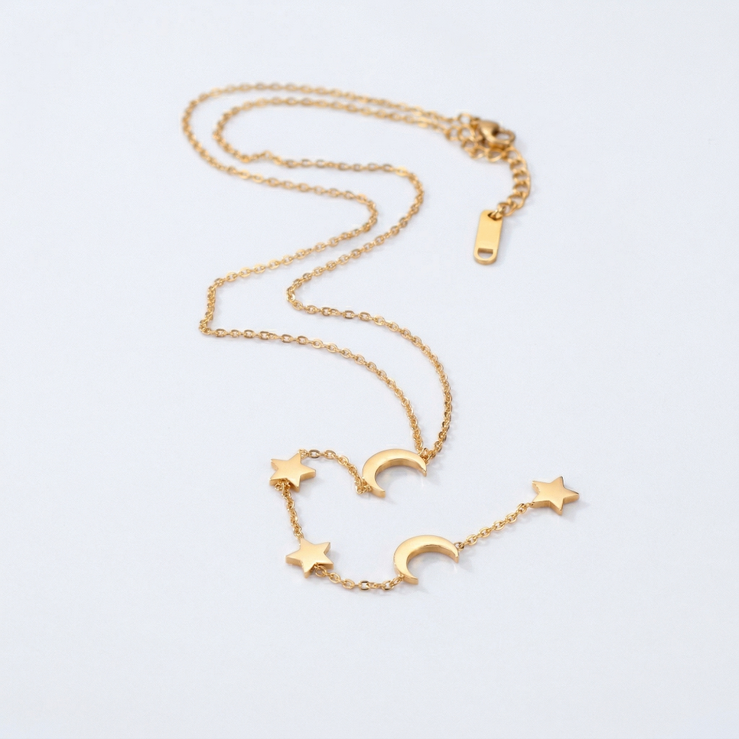 Gold necklace with star and moon charms on a light gray background