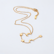 Gold necklace with star and moon charms on a light gray background
