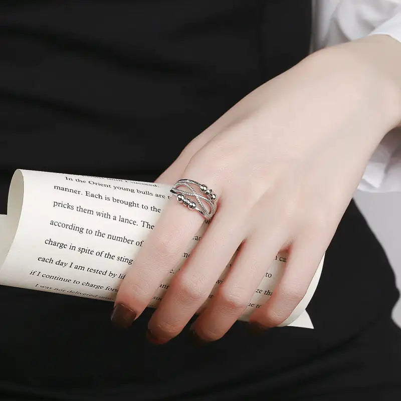 Hand wearing a silver ring on a book page
