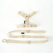 Beige dog harness and leash set on a white background