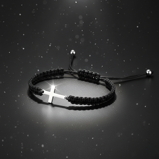 Black braided bracelet with a silver cross on a dark background