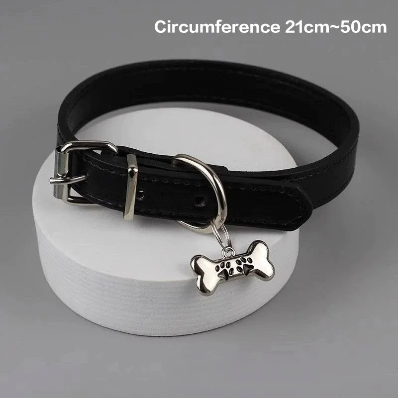 Black leather dog collar with a bone-shaped charm on a gray background