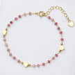Bracelet with pink beads and gold heart charms on a light background