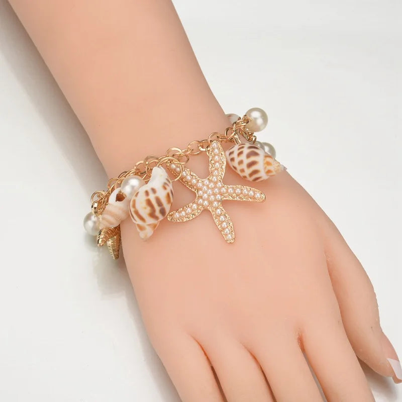Bracelet with starfish and shell designs on a hand against a white background
