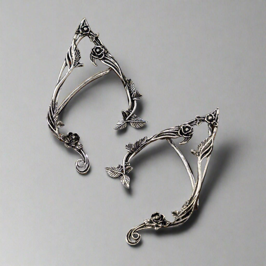 Pair of silver leaf-shaped earrings on a wooden surface