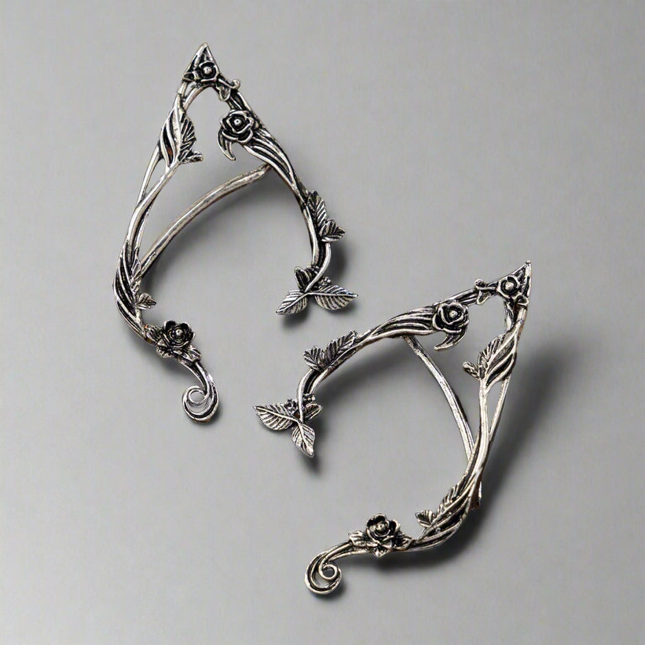 Pair of silver leaf-shaped earrings on a wooden surface