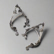 Pair of silver leaf-shaped earrings on a wooden surface