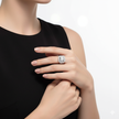 Close-up of a hand wearing a silver ring with a large diamond on a plain background