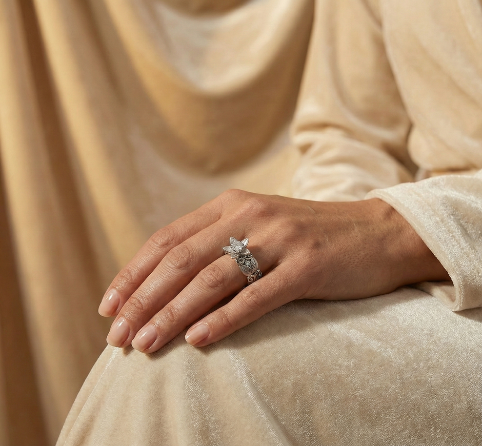 Hand wearing a silver Flower Proposal Ringon a beige fabric background