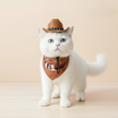 White cat wearing a brown cowboy hat and bandana on a beige background