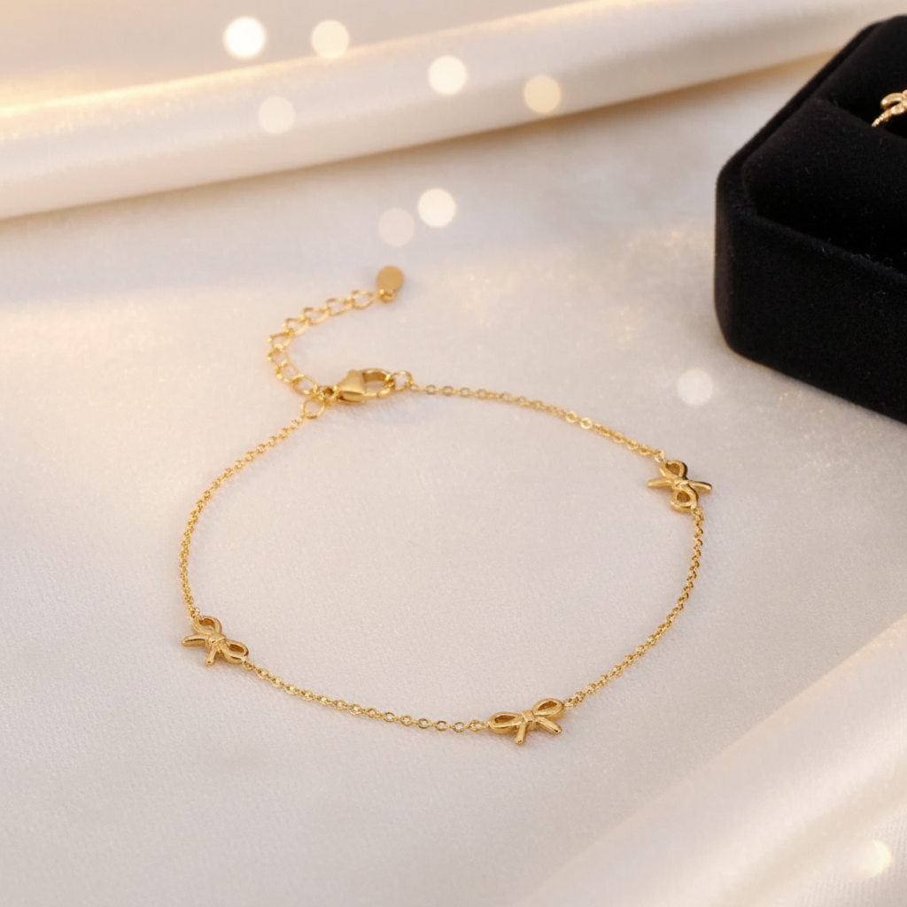 Gold ANKLET with bow charms on a white surface