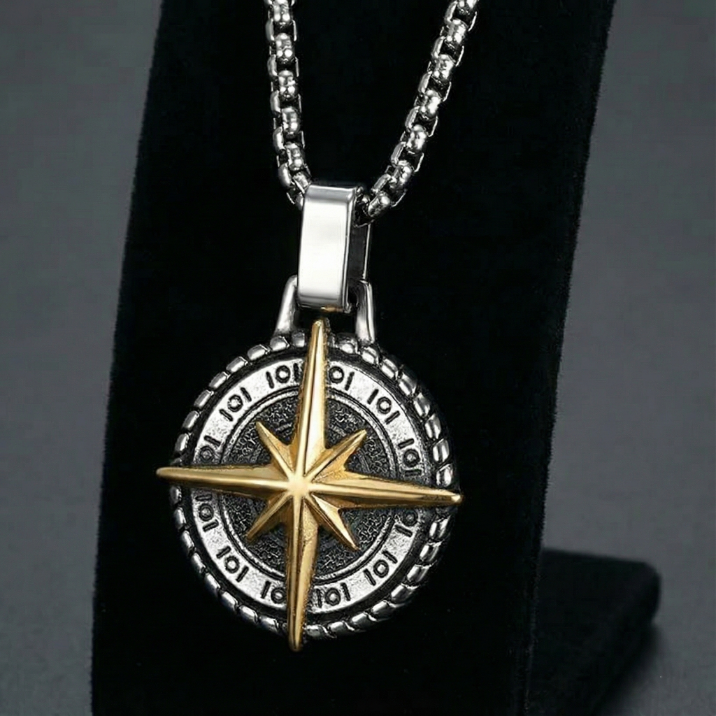 Necklace with a two-tone stainless steel compass pendant necklace on a black stand against a dark background