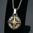 Necklace with a two-tone stainless steel compass pendant necklace on a black stand against a dark background