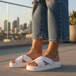 Person wearing white sandals with a cityscape in the background