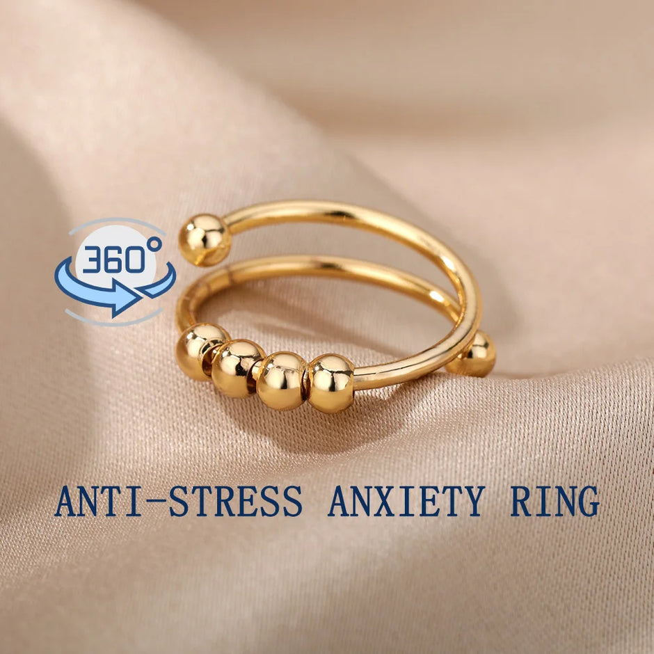 Gold anti-stress anxiety ring on a beige fabric background with '360' logo.