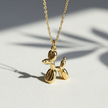 Gold balloon dog necklace on a light background