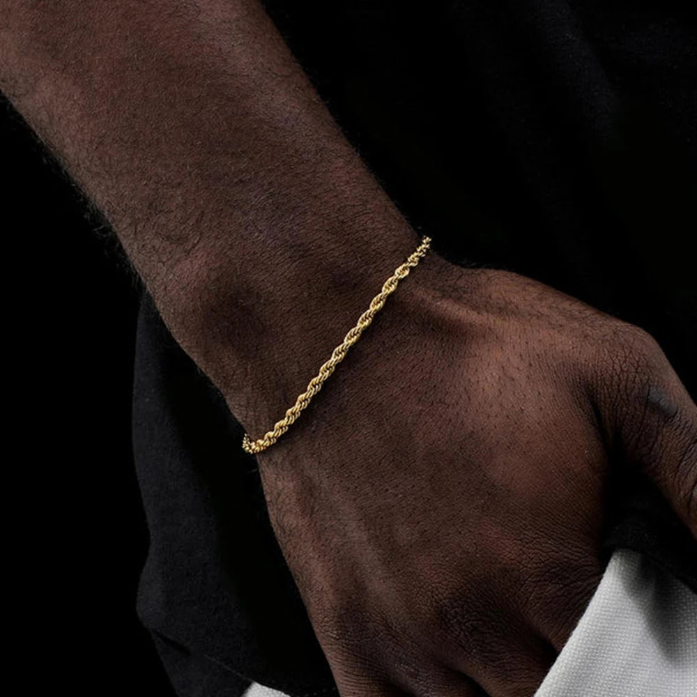 Gold bracelet on a person's wrist with a dark background