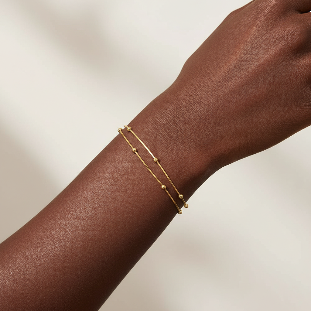 Gold bracelet on a wrist against a neutral background