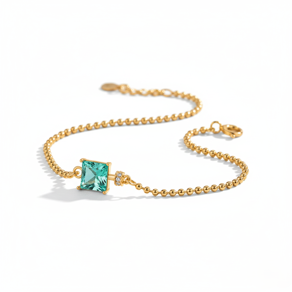 Gold bracelet with a green gemstone on a white background