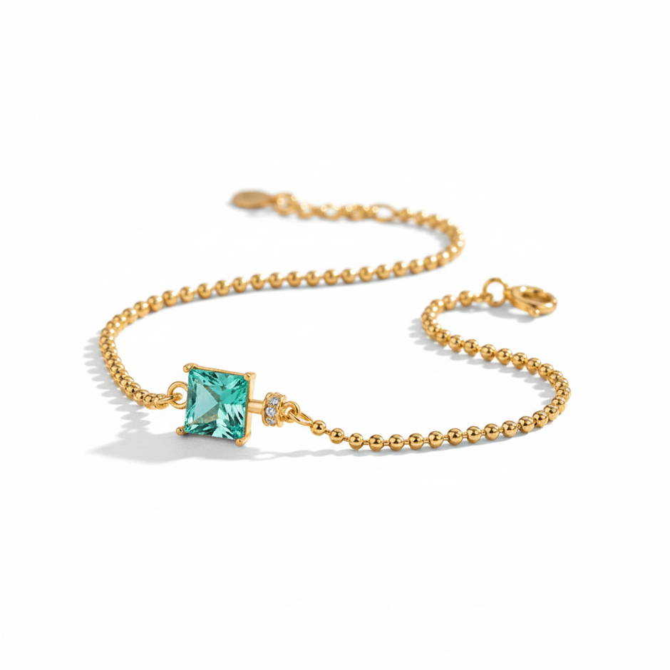 Gold bracelet with a green gemstone on a white background