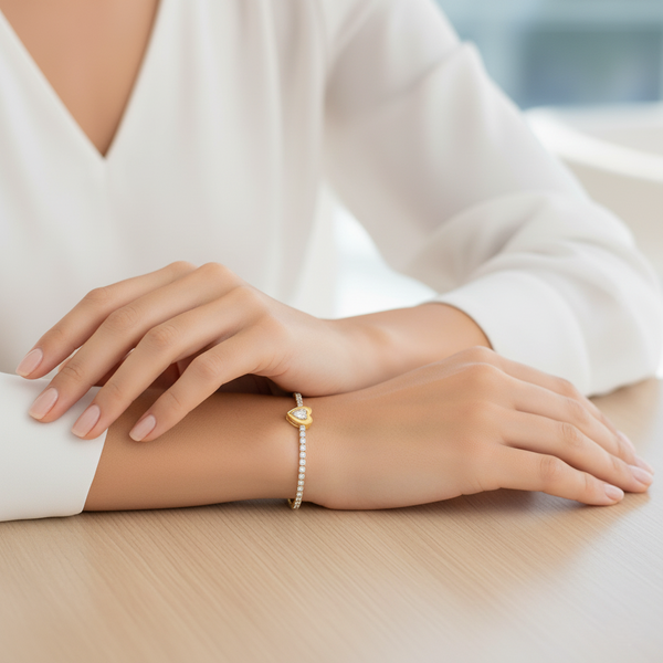 Close-up of a person's wrist wearing a gold bracelet on a light background