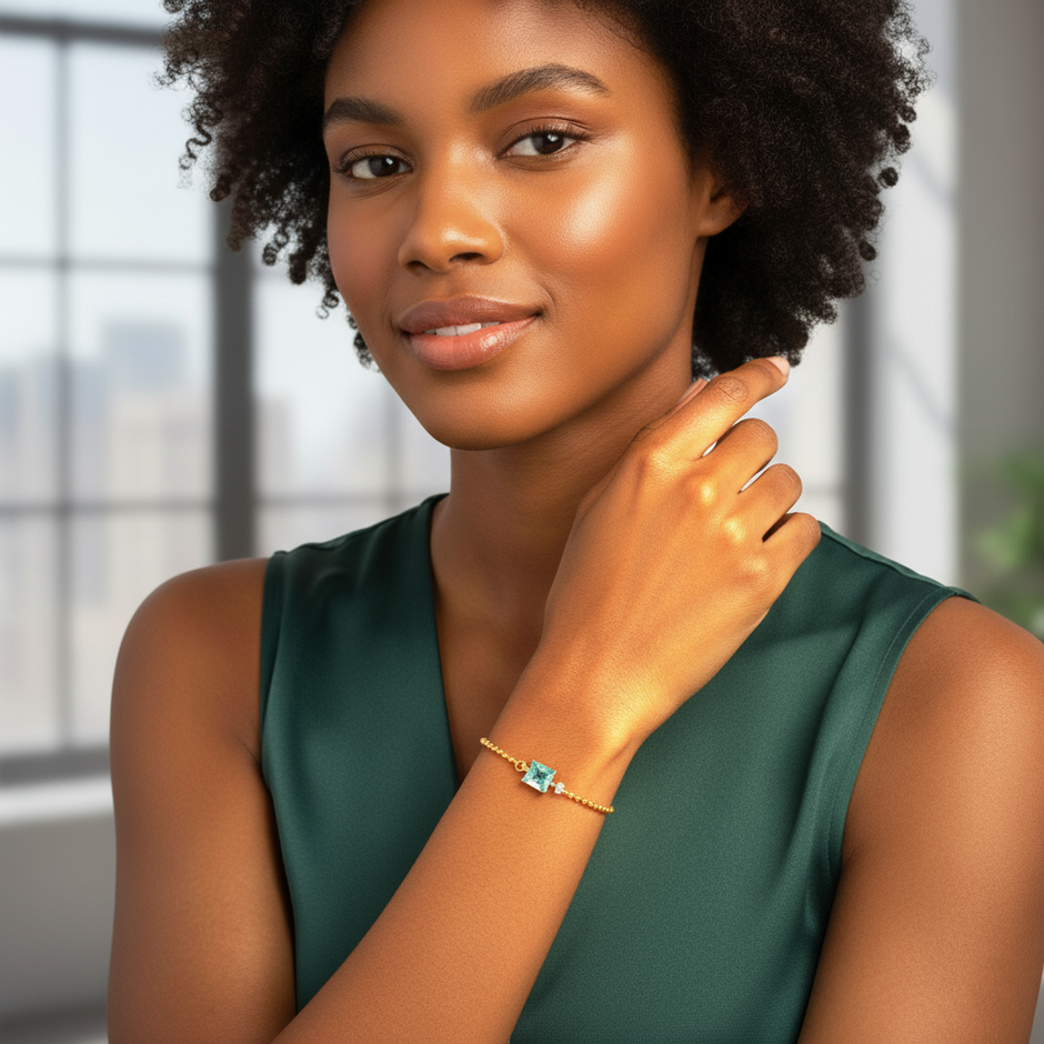 Woman wearing a green dress and gold bracelet with a blue gemstone indoors.