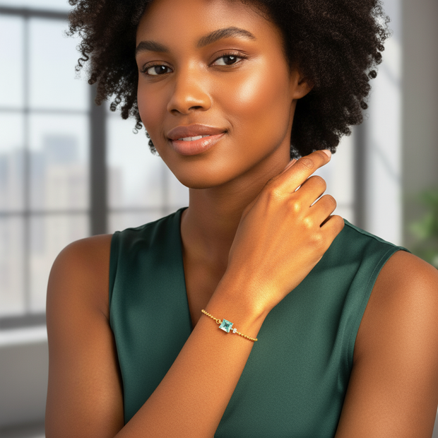 Woman wearing a green dress and gold bracelet with a blue gemstone indoors.