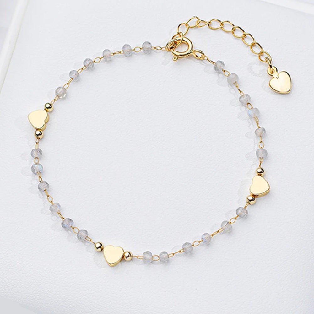 Gold bracelet with heart-shaped charms on a white surface