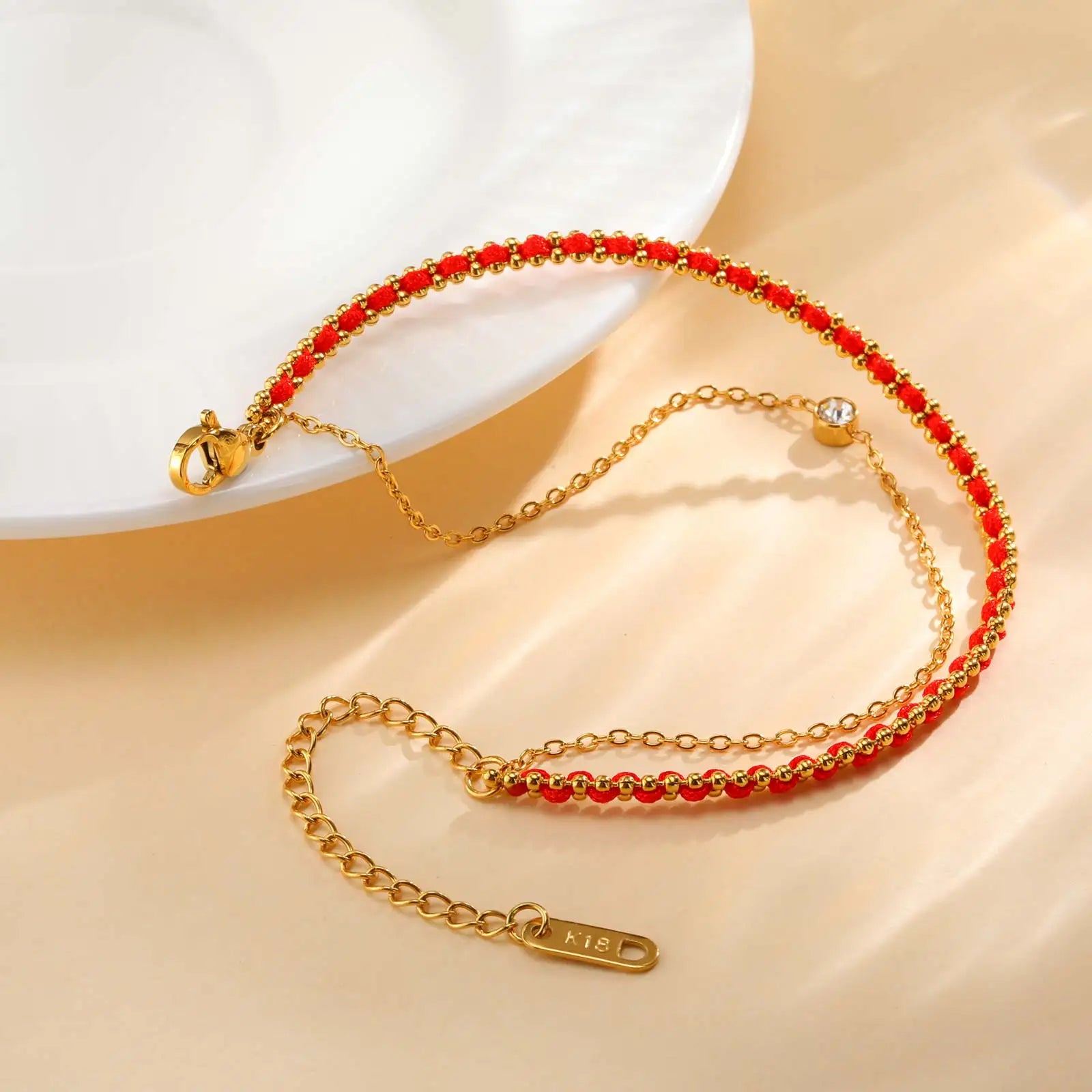 Gold bracelet with red beads on a beige surface