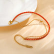 Gold bracelet with red beads on a beige surface