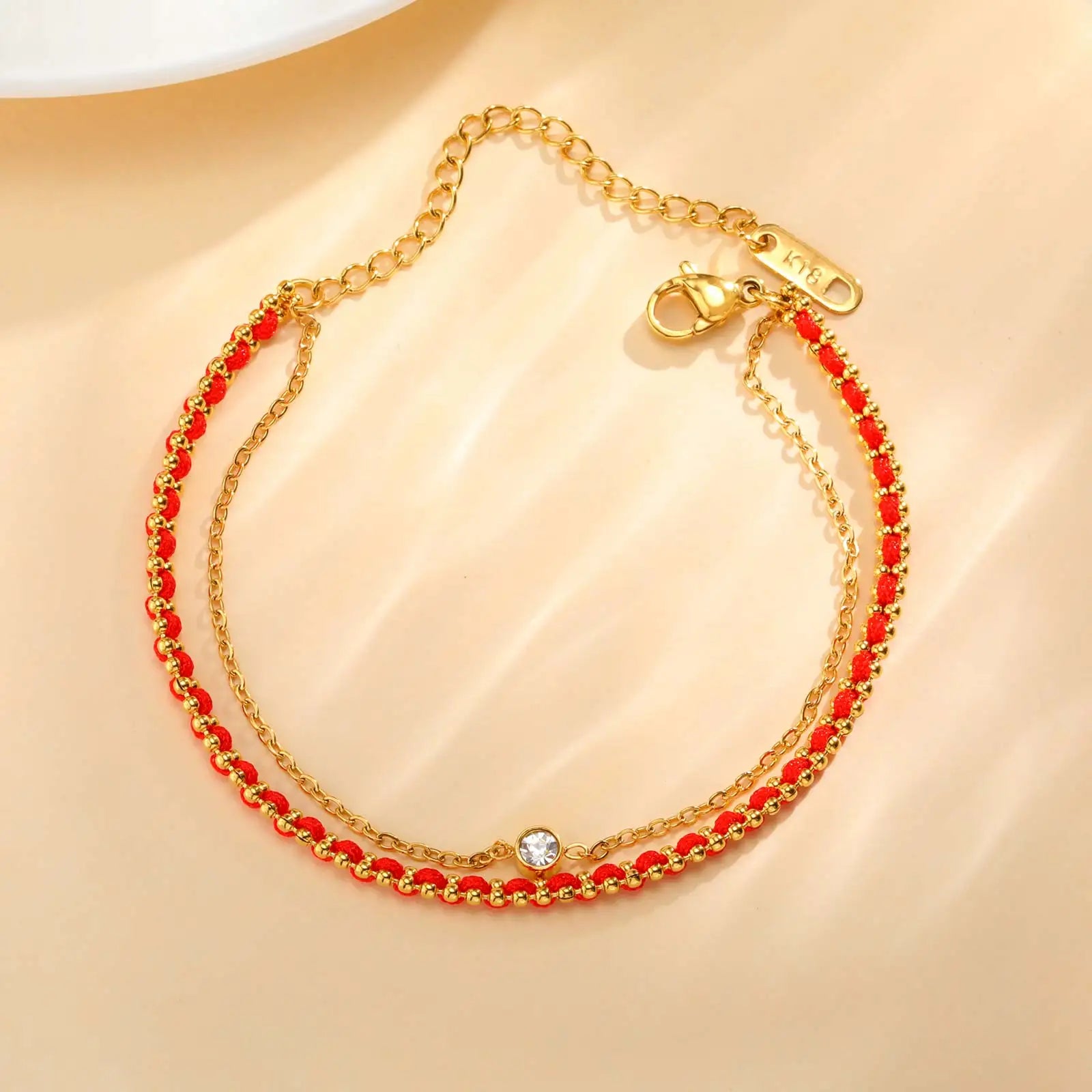 Gold bracelet with red beads on a beige background