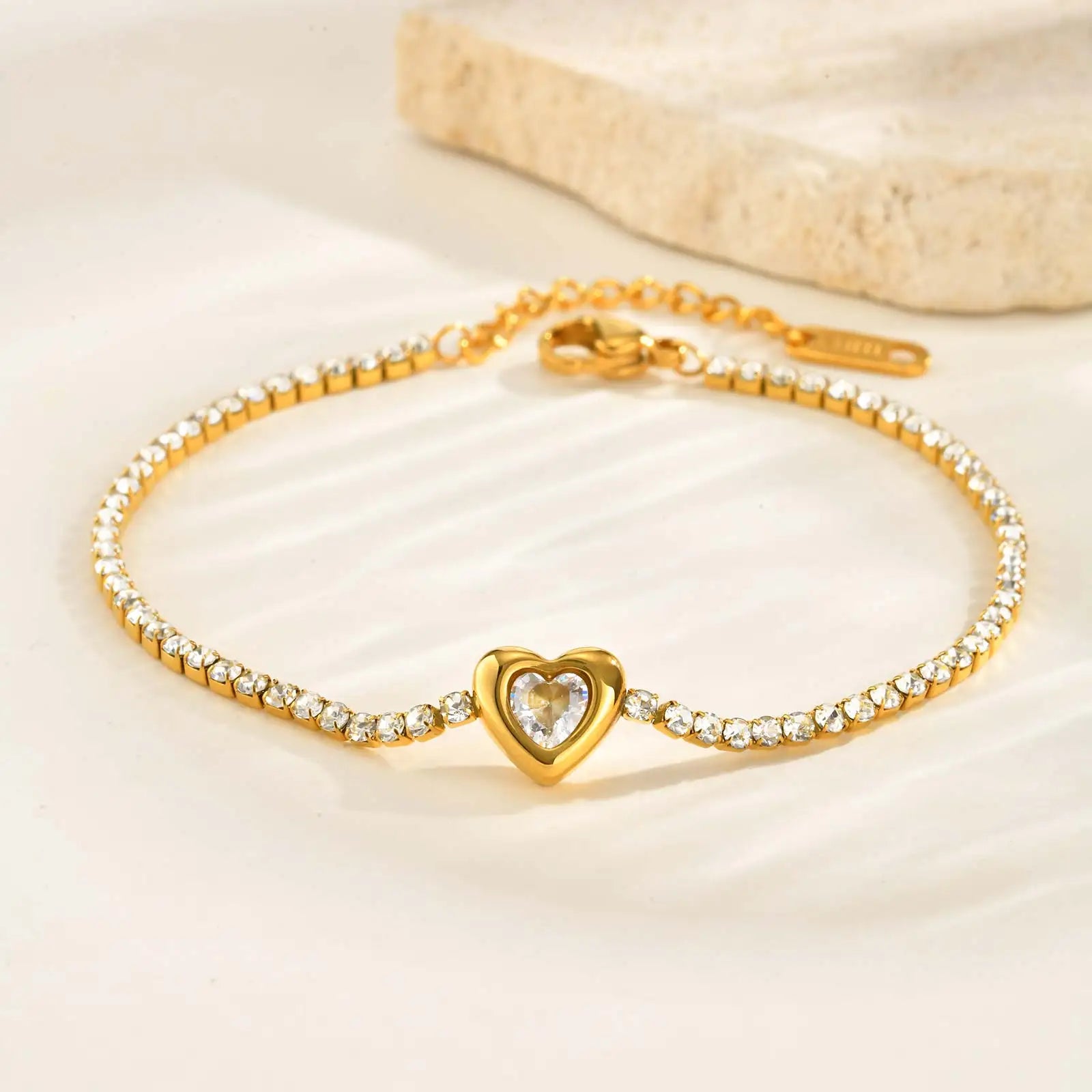 Gold bracelet with a heart-shaped clasp on a beige background