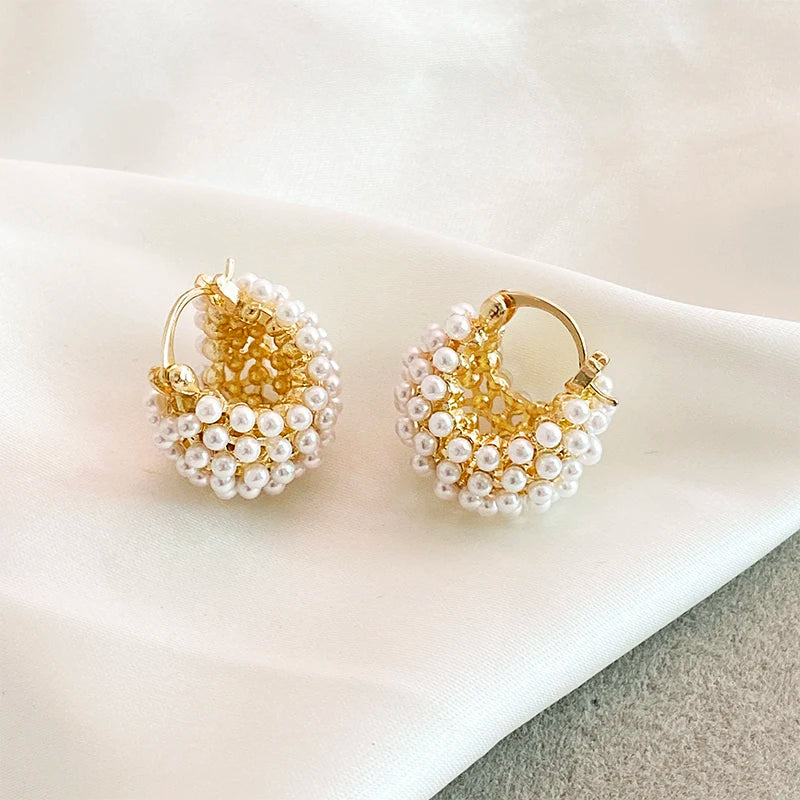 Gold hoop earrings with pearl beads on a light surface
