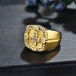 Gold ring with intricate design on a dark surface