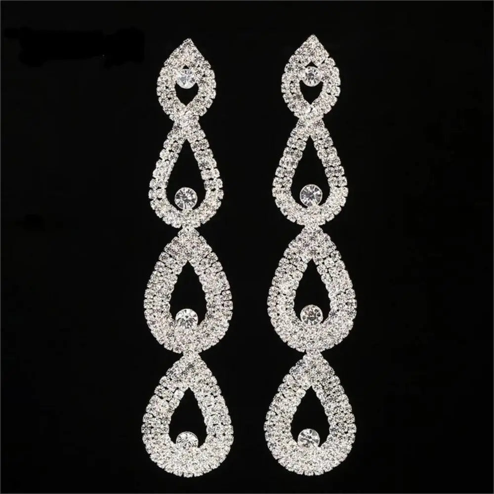 Pair of silver teardrop-shaped earrings with clear stones on a black background