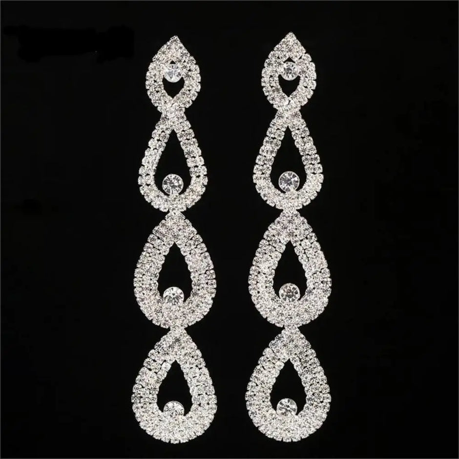 Pair of silver teardrop-shaped earrings with clear stones on a black background