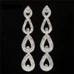 Pair of silver teardrop-shaped earrings with clear stones on a black background
