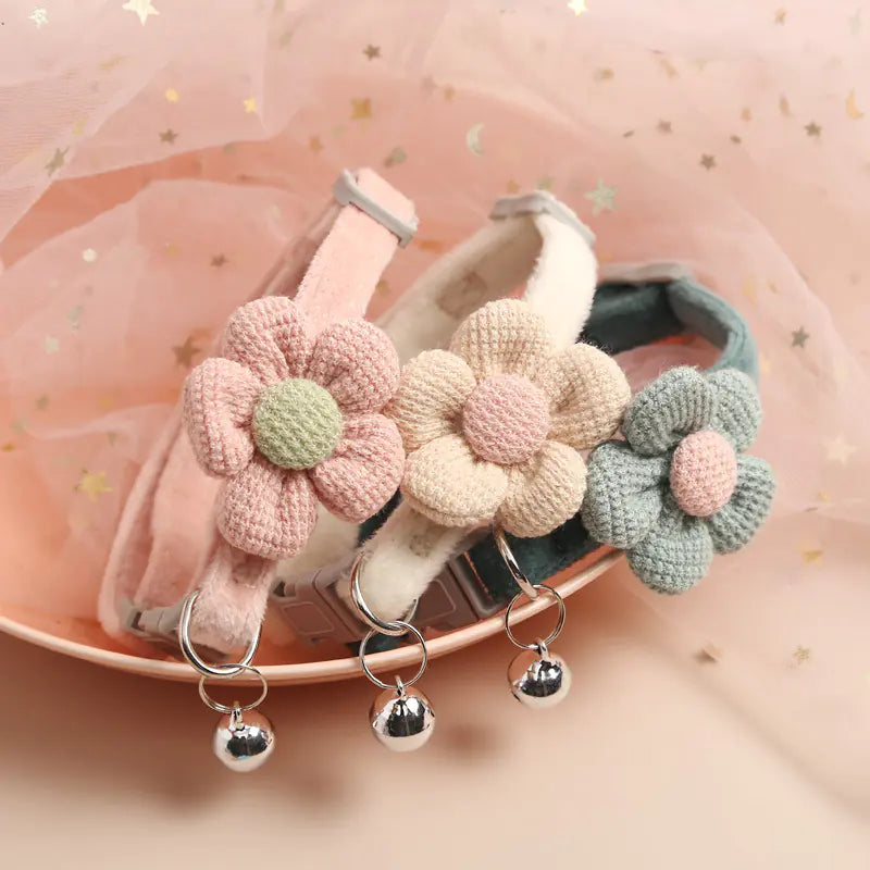 Three crocheted flower collars with bells on a pink background