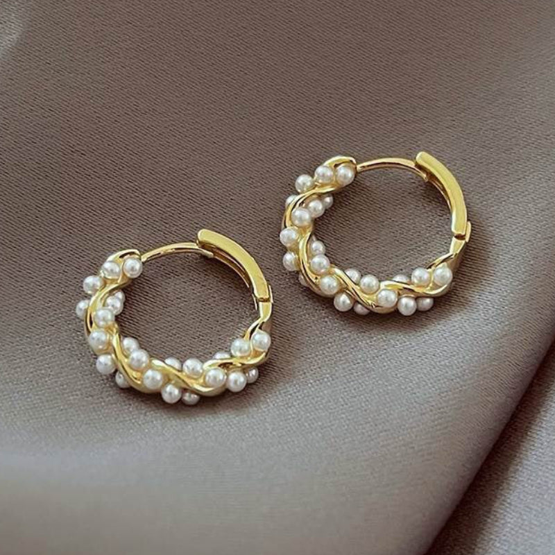 Gold hoop earrings with pearl accents on a soft brown background