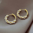 Gold hoop earrings with pearl accents on a soft brown background