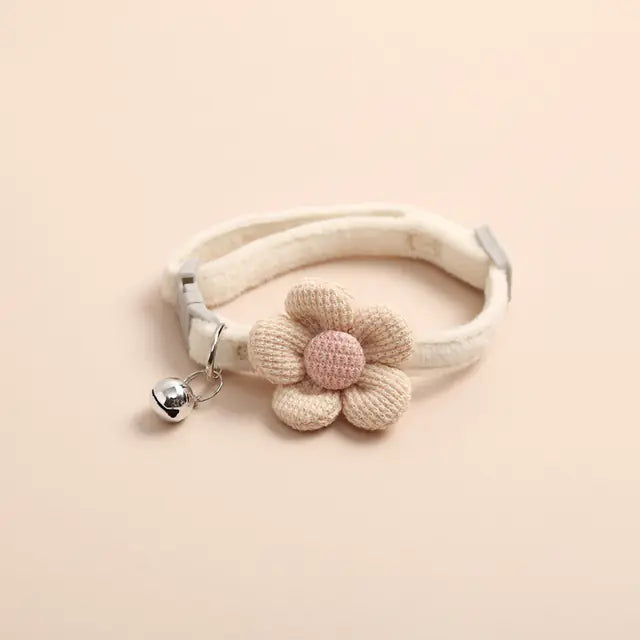 Cream-colored collar with a knitted flower and a small bell on a beige background 