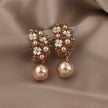 Pair of pearl earrings with floral details on a beige fabric background