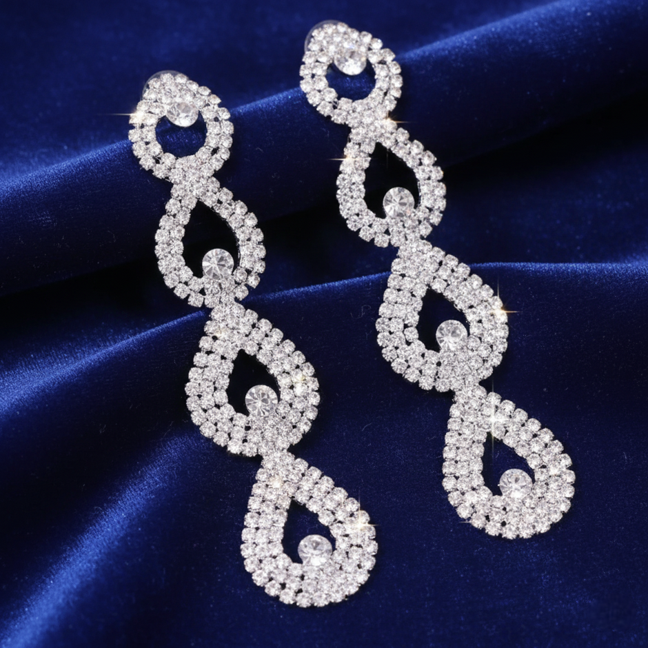 Pair of silver earrings with intricate designs on a blue fabric background