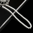 Pearl necklace on a black surface with a decorative brooch.